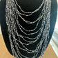 Multi-strand necklace of gray and iridescent beads on a black display
