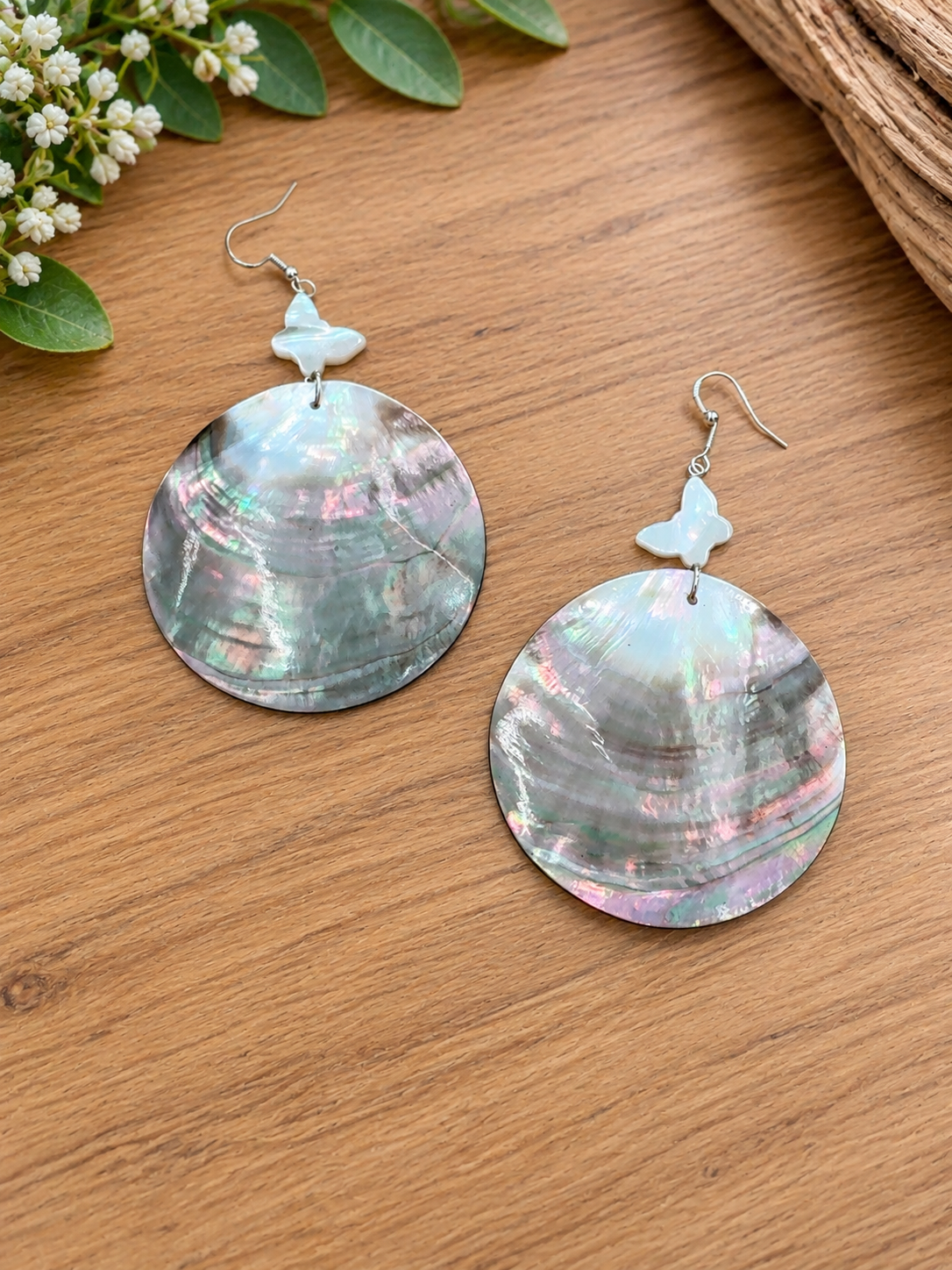 Round black lip shell earrings with small pale butterfly accents