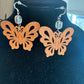 Openwork wooden butterfly earrings with faceted crystal accents on a black display