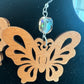 Close-up of a wooden butterfly earring and faceted crystal accent