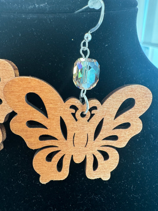Close-up of a wooden butterfly earring and faceted crystal accent